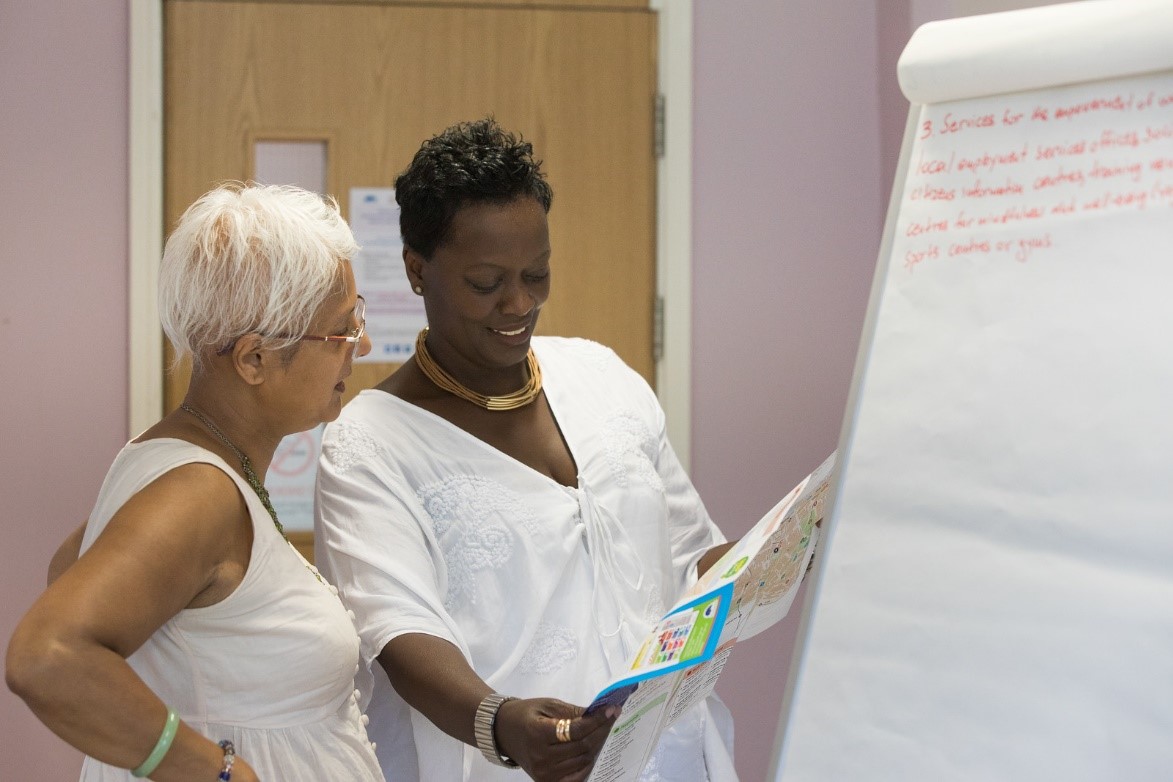 Two women standing in front of a white board, discussing and planning their investment strategy.