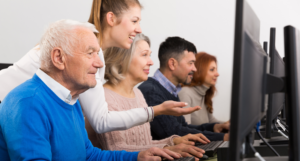 Tutor demonstrating to a mixed group of people how to use a computer