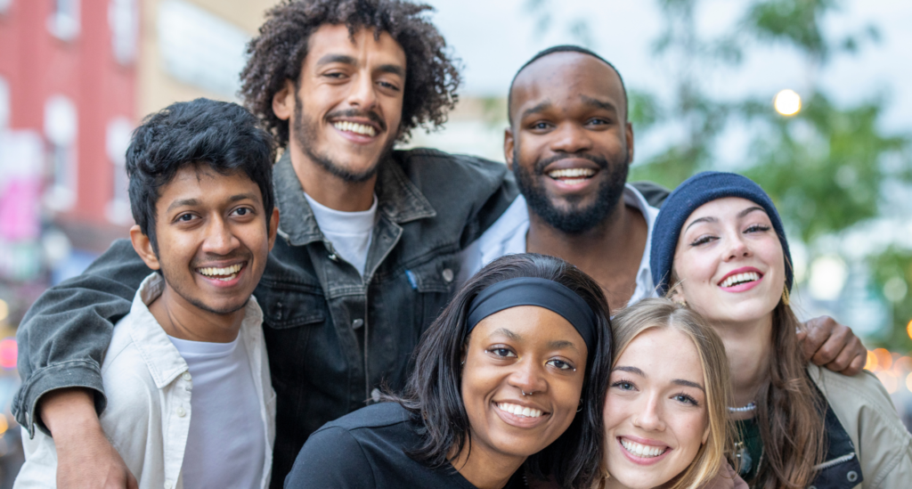 A diverse group of young people standing close together and looking happy representing the power of youth programmes