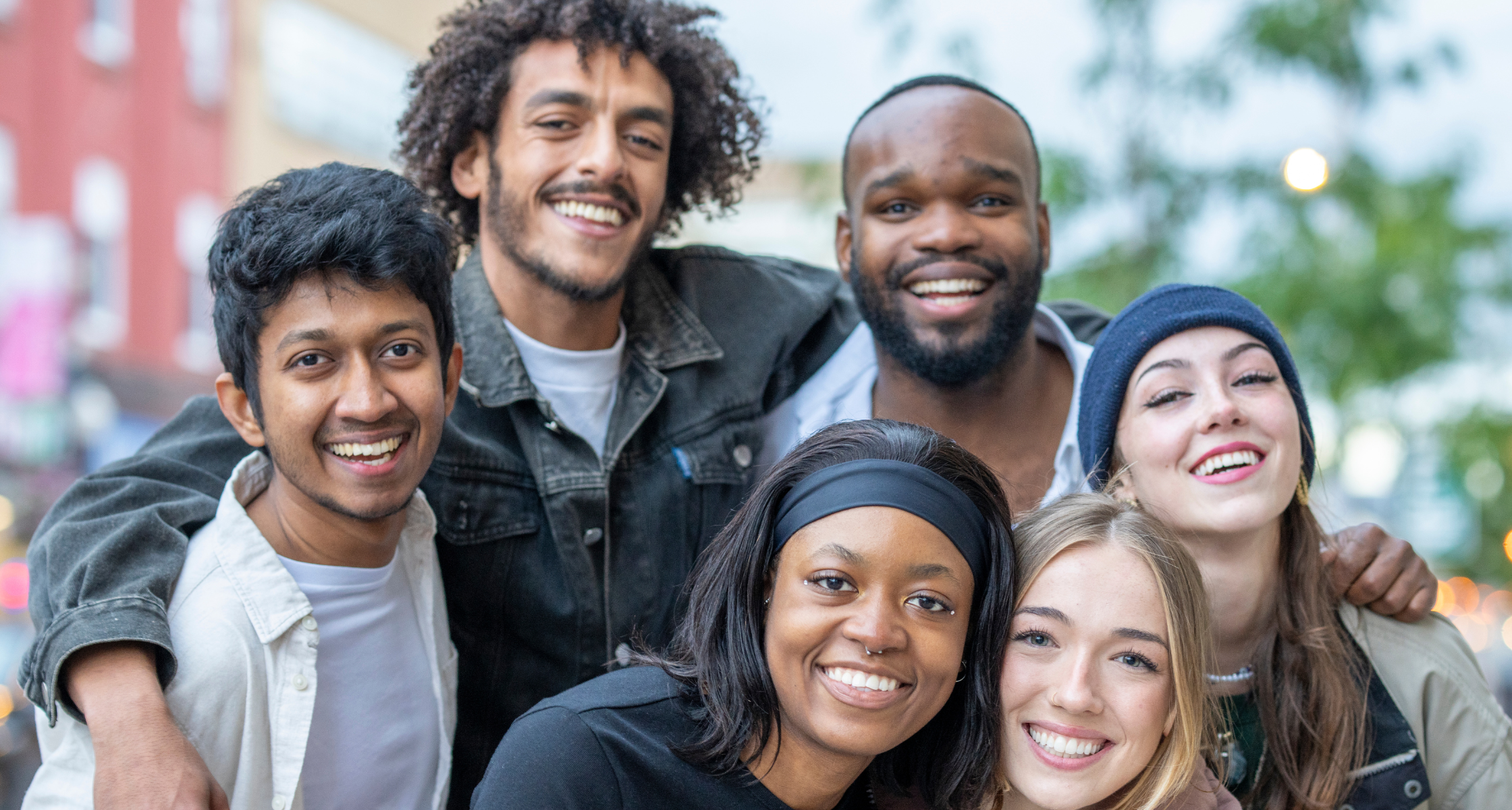 A diverse group of young people standing close together and looking happy representing the power of youth programmes