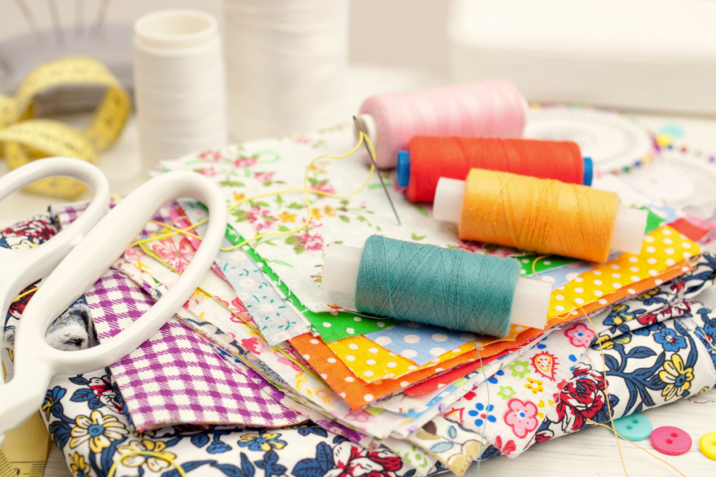 Various items for sewing such as threads, fabric and scissors on a table for Introduction to Sewing and Mending